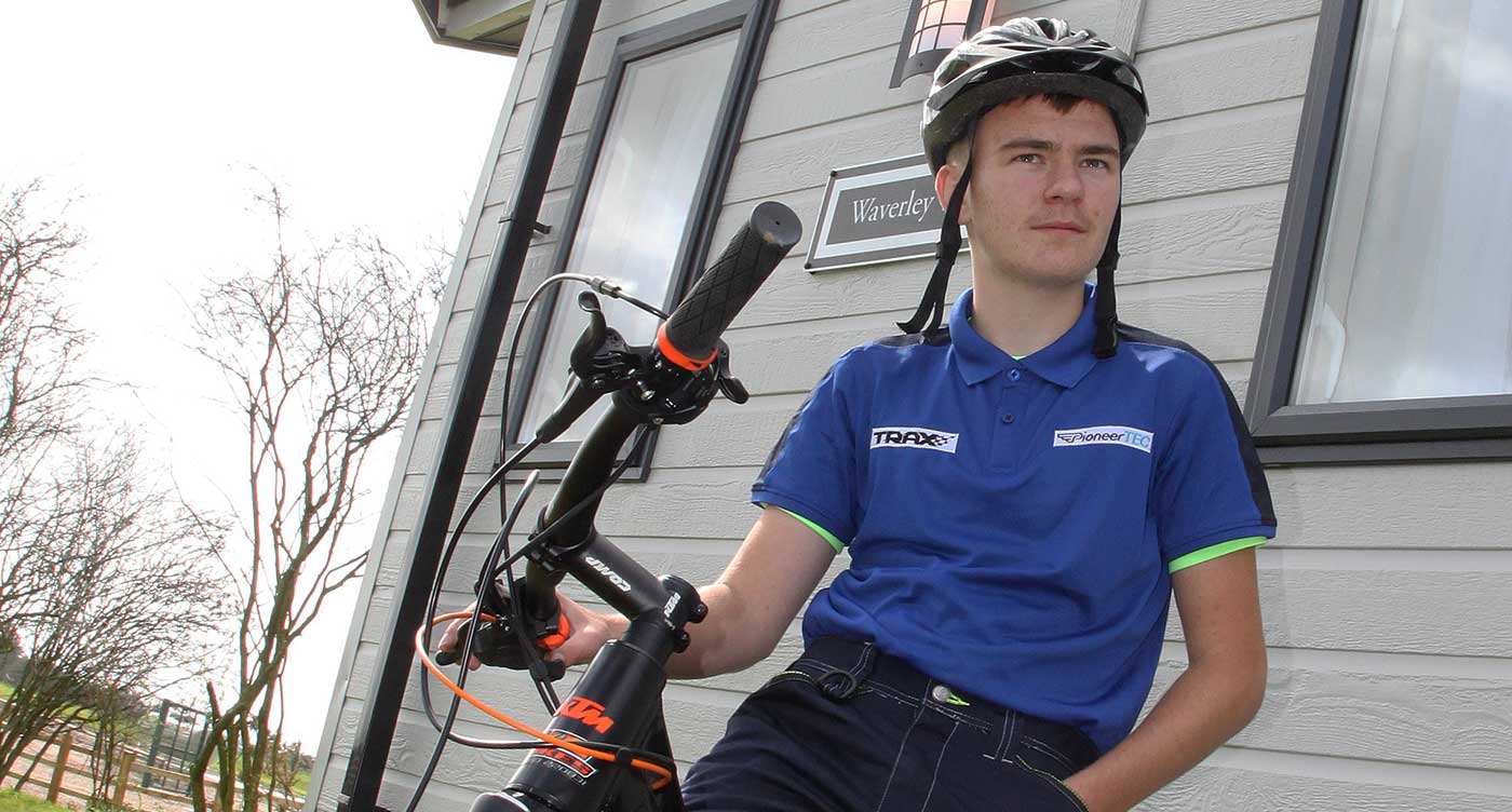 student in front of lodge on bike